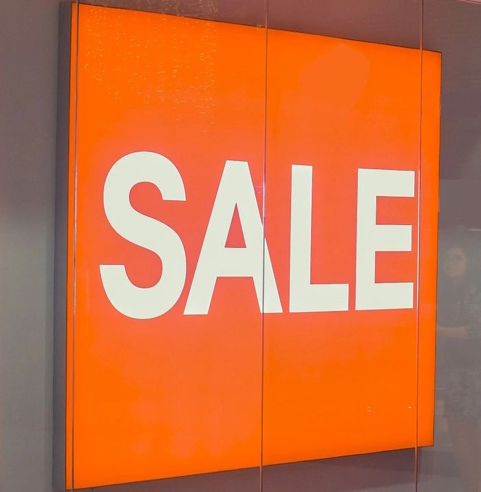 Vitrine contenant un panneau lumineux de couleur orange avec l' inscription Sale